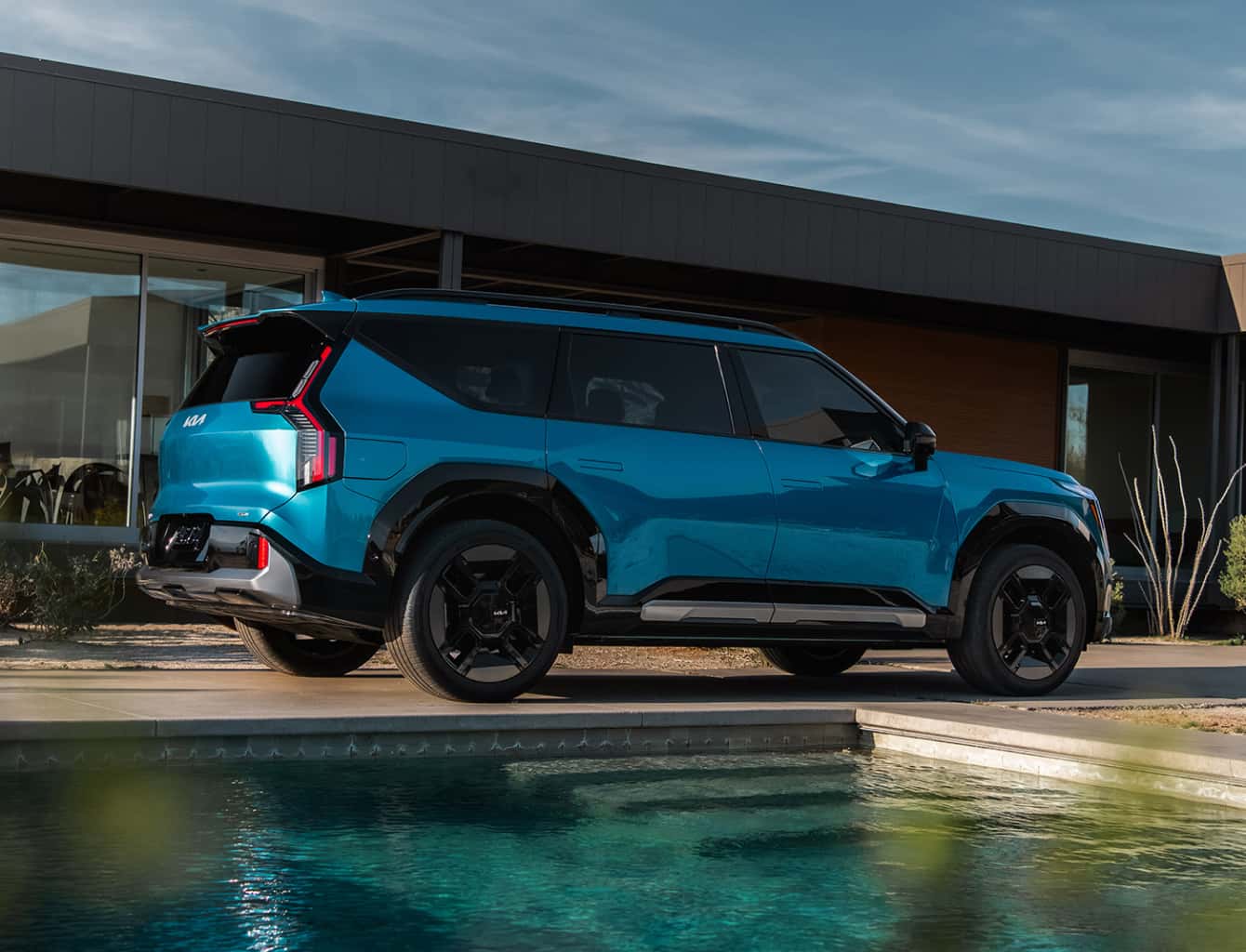 EV9 parked next to a modern design house and inground pool